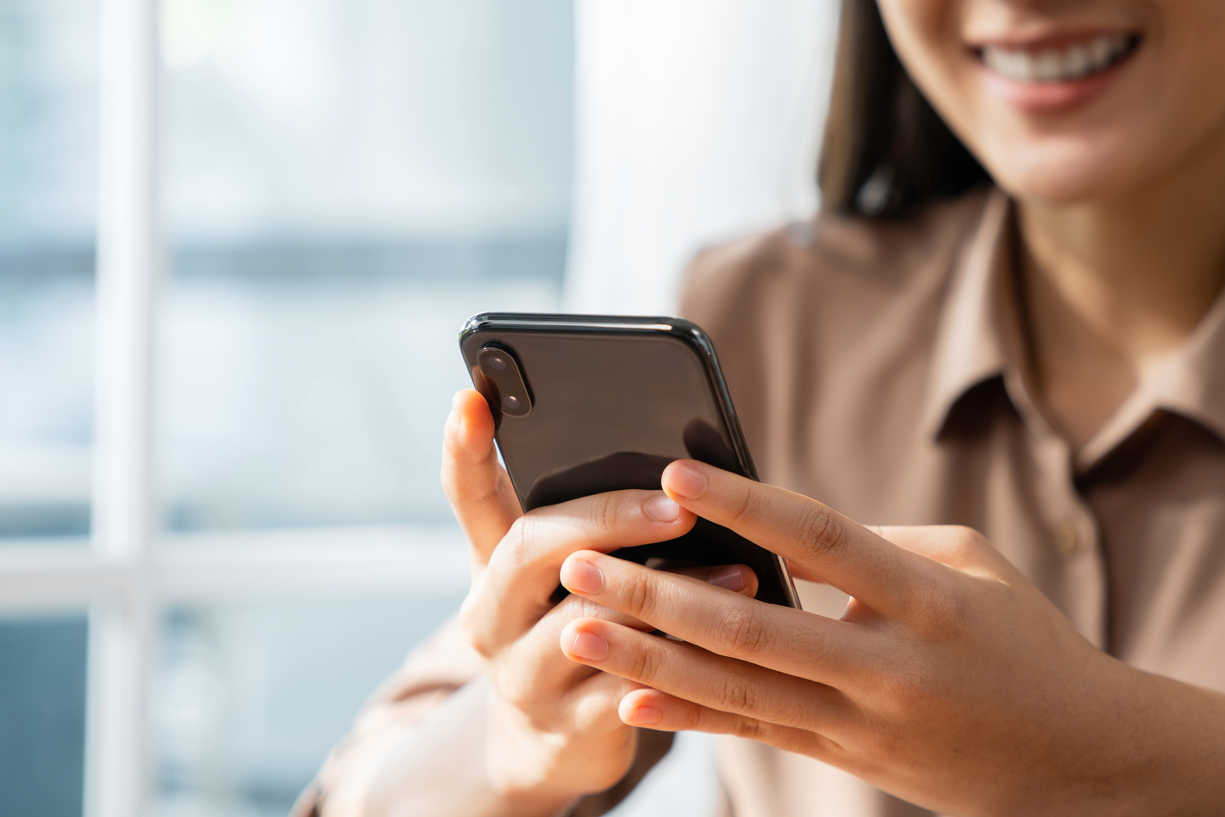 A woman looking into a mobile phone and smiling